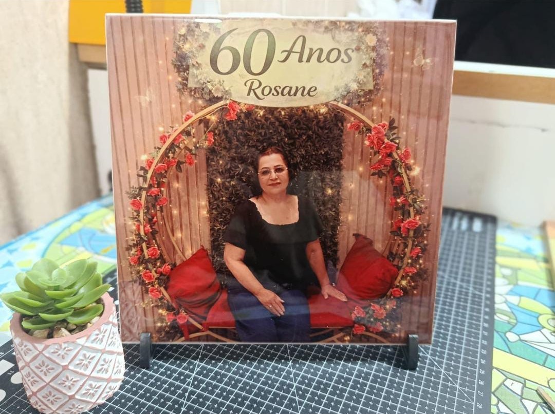 Azulejo quadrado em suporte, com foto de aniversariante em arco de rosas vermelhas e o texto 60 Anos Rosane