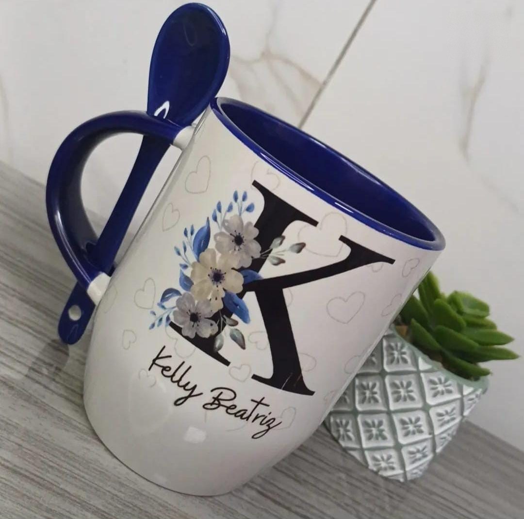 Caneca branca com interior, alça e colher azul-marinho, letra K grande com flores azuis e o nome Kelly Beatriz