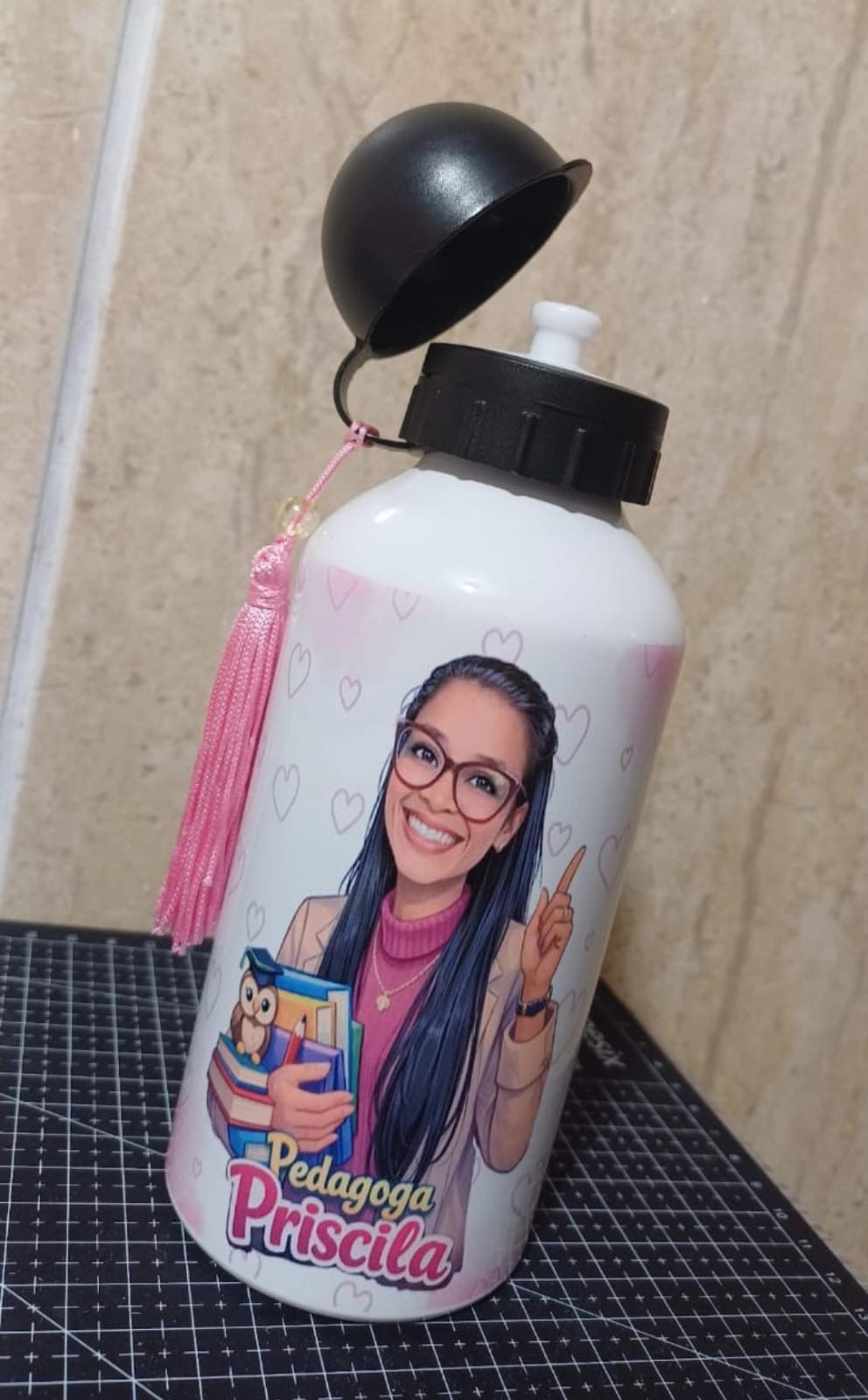 Squeeze branco com tassel rosa e caricatura de uma pedagoga segurando livros, com o texto Pedagoga Priscila